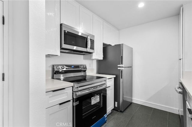 kitchen featuring stainless steel appliances, white cabinetry, and dark tile patterned flooring