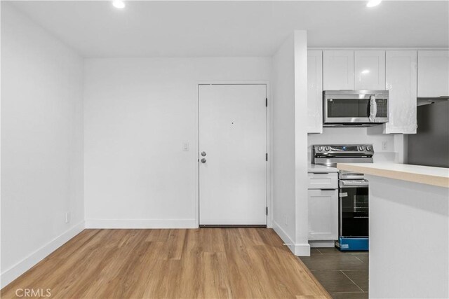 kitchen with light hardwood / wood-style floors, white cabinets, and stainless steel appliances