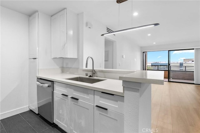 kitchen featuring kitchen peninsula, decorative light fixtures, dishwasher, white cabinets, and sink