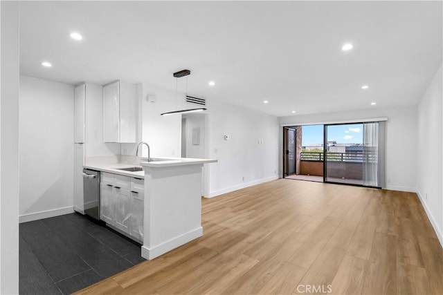 kitchen featuring white cabinetry, kitchen peninsula, hanging light fixtures, stainless steel dishwasher, and sink