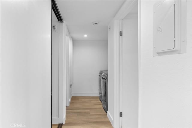 hall featuring light wood-type flooring, electric panel, and washer and clothes dryer