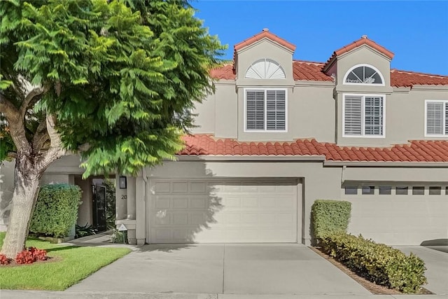 view of front of property with stucco siding, concrete driveway, an attached garage, and a tiled roof