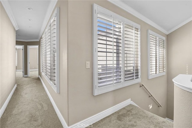 corridor with baseboards, carpet floors, an upstairs landing, and crown molding