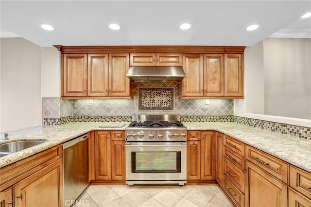 kitchen featuring brown cabinets, under cabinet range hood, appliances with stainless steel finishes, light tile patterned floors, and light stone countertops