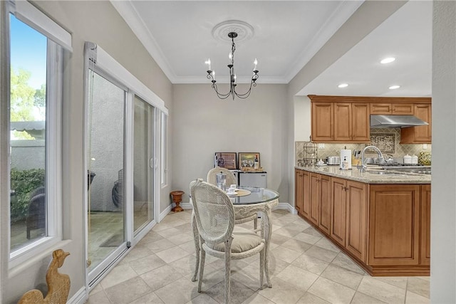 kitchen featuring light stone countertops, baseboards, ornamental molding, under cabinet range hood, and backsplash