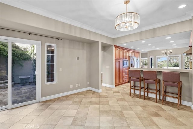 kitchen with a notable chandelier, stainless steel appliances, a kitchen bar, and baseboards