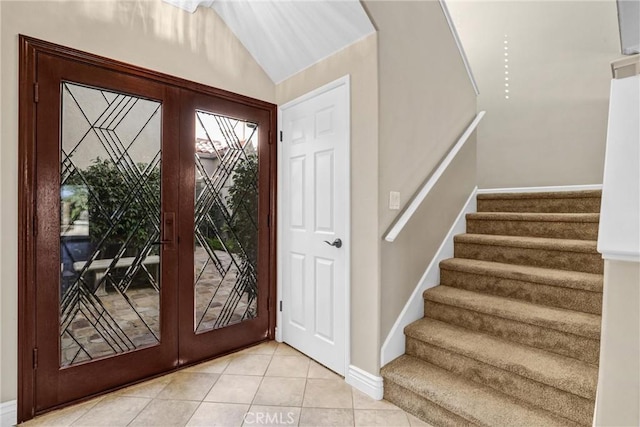 foyer entrance featuring light tile patterned floors, french doors, stairs, and lofted ceiling