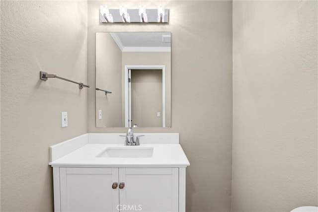 bathroom with a textured wall, vanity, and crown molding