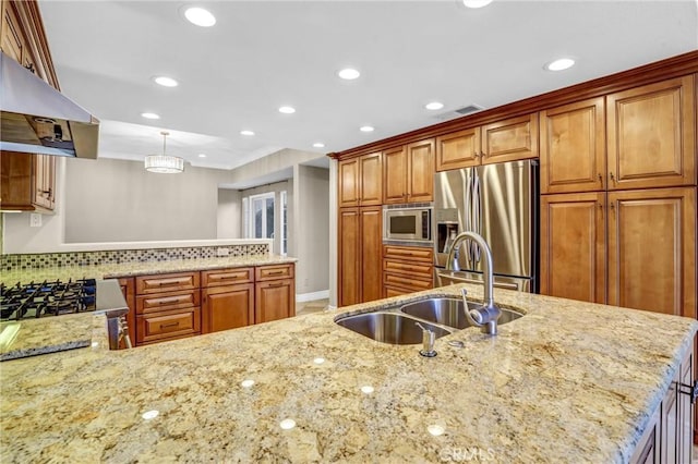 kitchen featuring brown cabinets, a sink, light stone counters, under cabinet range hood, and stainless steel appliances