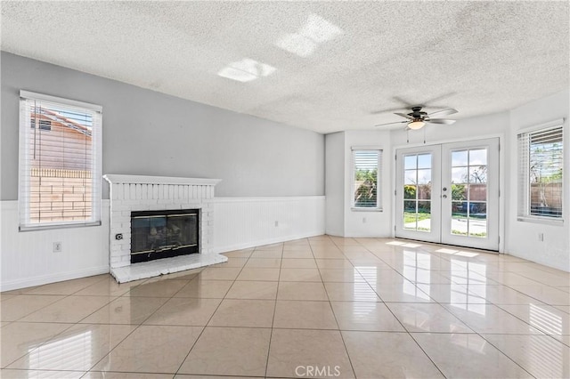 unfurnished living room featuring a healthy amount of sunlight, french doors, and a fireplace