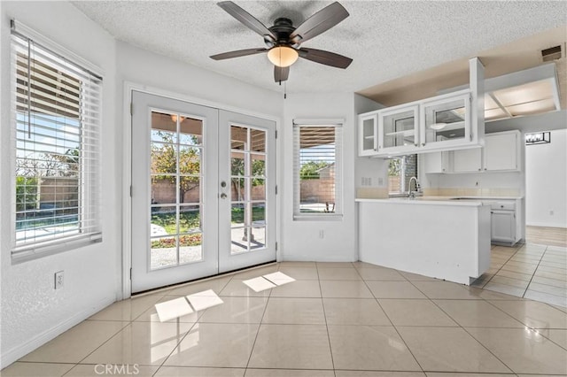 doorway featuring light tile patterned floors, french doors, and a textured ceiling