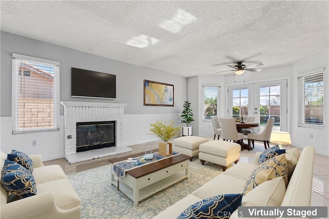 living room with a textured ceiling, light tile patterned floors, french doors, and a fireplace