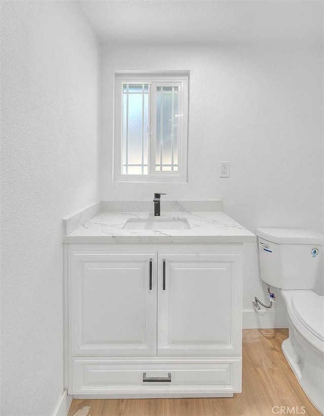 bathroom featuring toilet, hardwood / wood-style floors, and vanity