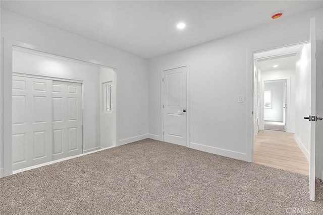 unfurnished bedroom featuring a closet and light carpet