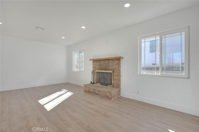 unfurnished living room featuring light hardwood / wood-style floors and a stone fireplace