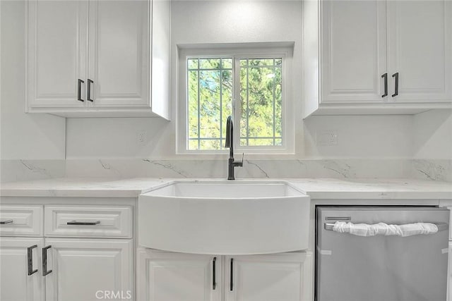 kitchen with light stone countertops, white cabinetry, and sink