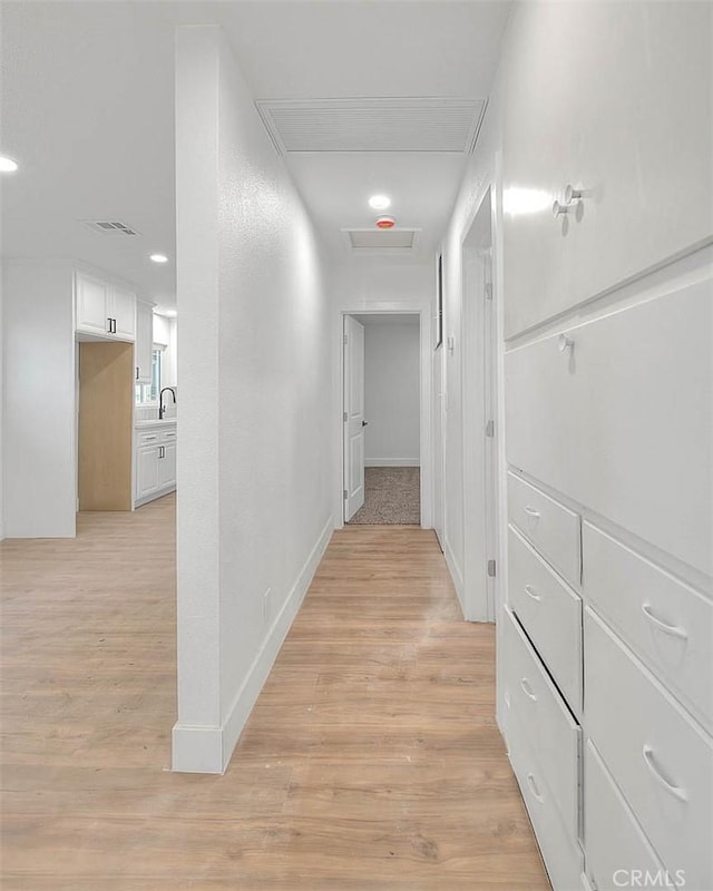 hallway with light hardwood / wood-style floors and sink