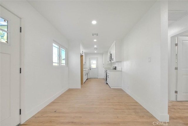 corridor with a wealth of natural light and light hardwood / wood-style floors