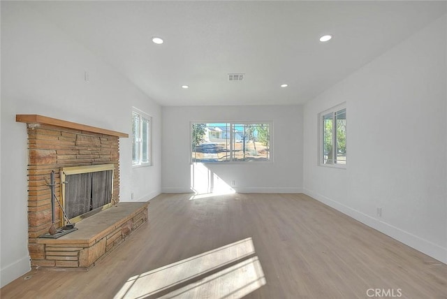 unfurnished living room featuring a stone fireplace and light hardwood / wood-style floors