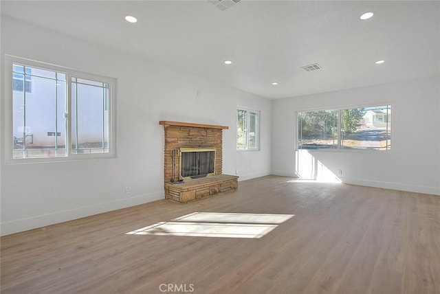 unfurnished living room featuring light hardwood / wood-style floors and a stone fireplace