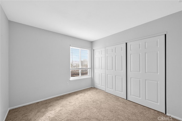 unfurnished bedroom featuring light colored carpet and a closet