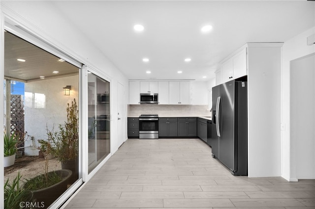 kitchen featuring backsplash, gray cabinets, light hardwood / wood-style floors, appliances with stainless steel finishes, and white cabinets