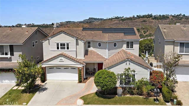 2438 Calle Aquamarina, San Clemente, CA 92673 - view of front of property featuring a tile roof, concrete driveway, roof mounted solar panels, an attached garage, and stucco siding