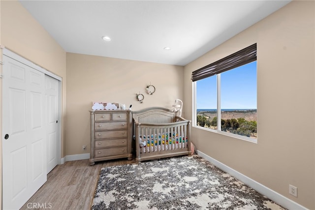 bedroom featuring a closet, light wood-type flooring, and a nursery area