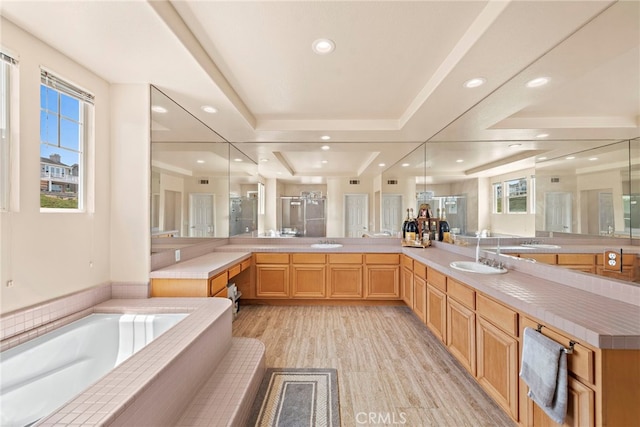 bathroom featuring wood-type flooring, a tray ceiling, vanity, and shower with separate bathtub