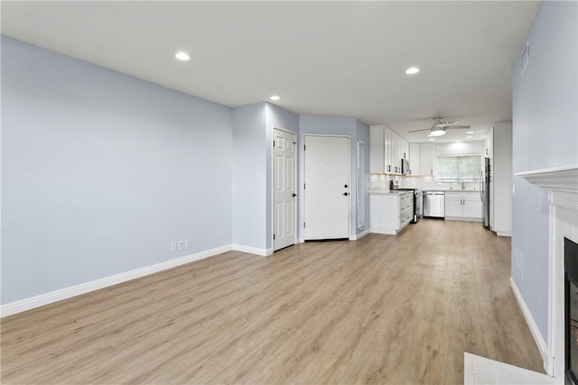 unfurnished living room with ceiling fan, light wood-type flooring, and sink