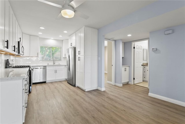 kitchen with stainless steel appliances, light hardwood / wood-style flooring, white cabinetry, and sink