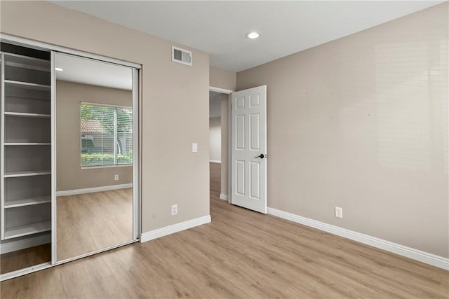 unfurnished bedroom with a closet and light hardwood / wood-style floors