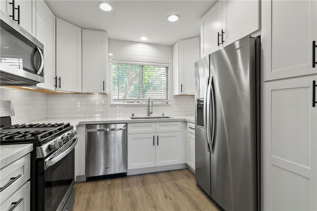 kitchen with light hardwood / wood-style floors, stainless steel appliances, tasteful backsplash, white cabinets, and sink