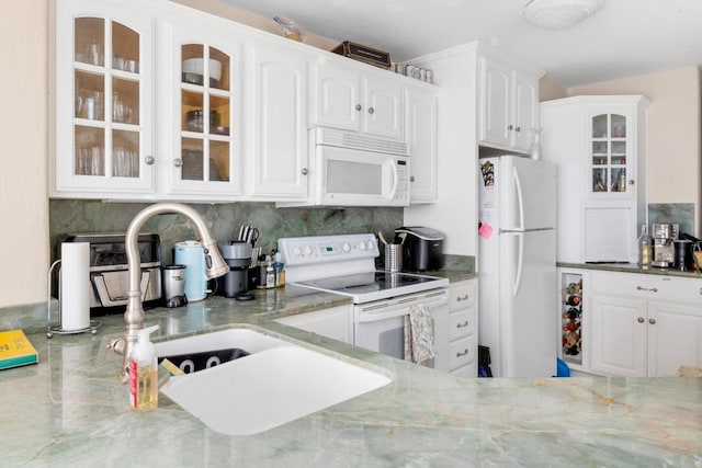 kitchen featuring decorative backsplash, dark stone counters, white appliances, and white cabinetry