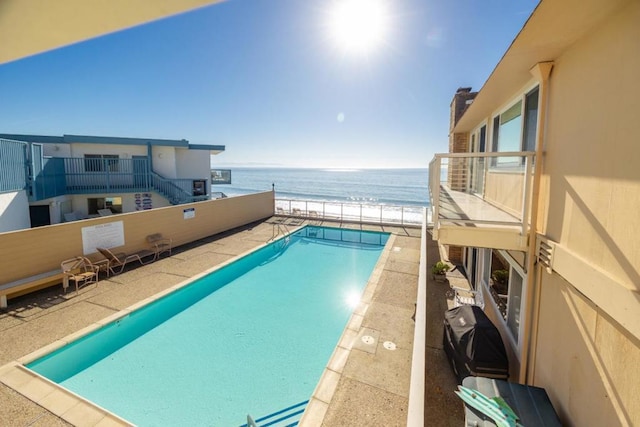 view of swimming pool with a water view and a beach view