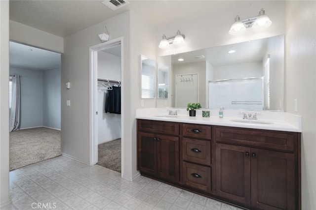 bathroom featuring a shower with door and vanity