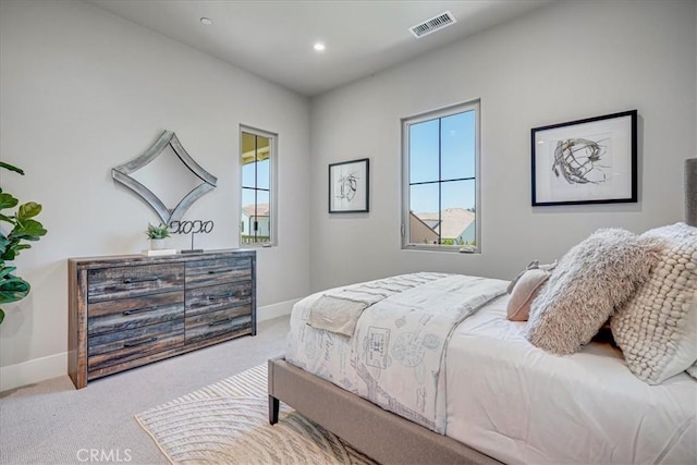 bedroom featuring light carpet, multiple windows, visible vents, and baseboards