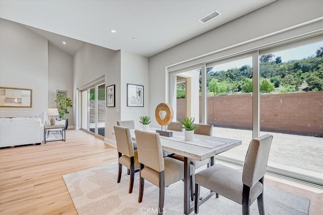 dining space featuring recessed lighting, a high ceiling, visible vents, baseboards, and light wood finished floors