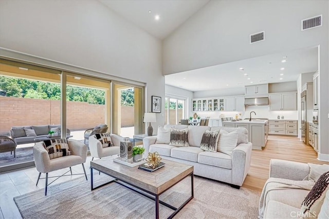 living area with high vaulted ceiling, recessed lighting, visible vents, and light wood-style flooring