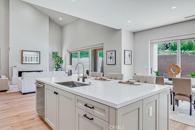 kitchen with light countertops, visible vents, open floor plan, a healthy amount of sunlight, and a sink