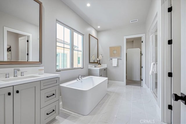 full bath featuring visible vents, a sink, a freestanding bath, two vanities, and recessed lighting