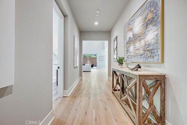 hallway featuring light wood-type flooring and baseboards