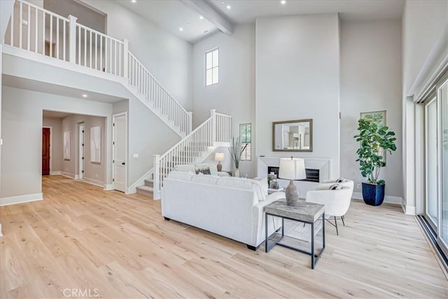 living room with a high ceiling, light hardwood / wood-style flooring, and beam ceiling