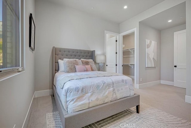 bedroom featuring recessed lighting, a spacious closet, baseboards, and light colored carpet