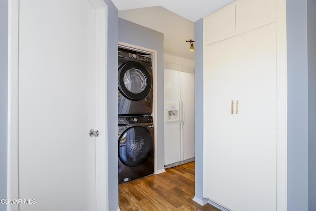 laundry room featuring dark wood-type flooring and stacked washer / dryer