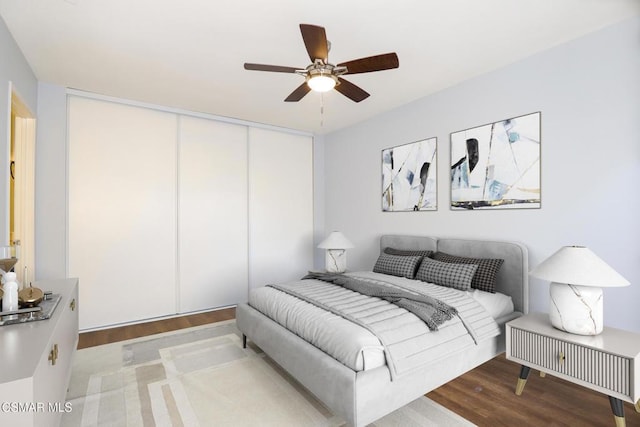 bedroom featuring ceiling fan, a closet, and light hardwood / wood-style flooring