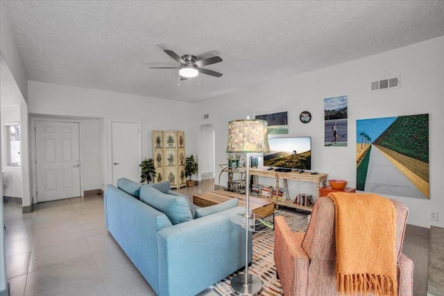 living room with ceiling fan and a textured ceiling