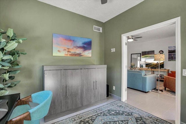 interior space featuring light tile patterned flooring, ceiling fan, and a textured ceiling