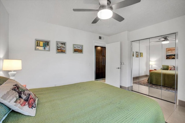 bedroom featuring light tile patterned floors, ceiling fan, and a closet