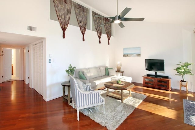 living room featuring ceiling fan, a high ceiling, and dark hardwood / wood-style floors